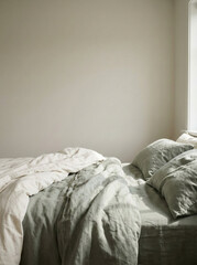 Minimalist bedroom interior with an unmade bed and soft natural sunlight casting gentle shadows on neutral walls