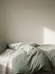 Minimalist bedroom interior with an unmade bed and soft natural sunlight casting gentle shadows on neutral walls