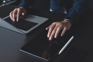 Man using digital tablet and working on laptop computer on office table. Business man touching on...
