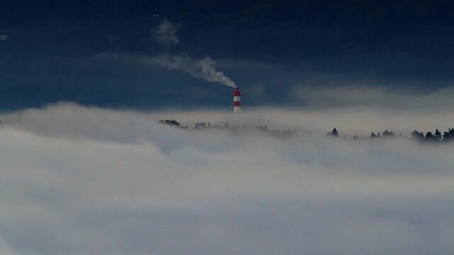 tall factory chimney smoking above polluted inversion