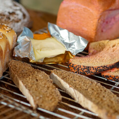 Close-up of fresh artisan bread slices with butter on a cooling rack. Rustic homemade baking concept with whole grain bread, seeds, and natural textures in warm kitchen light