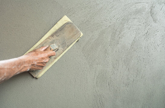 Hand worker polished wet motar rough with sponge trowel for smoothing plaster surface wall texture background construction house site