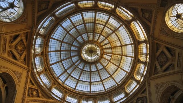 Ornate dome, viewed from below, featuring intricate gold carvings and glass panes