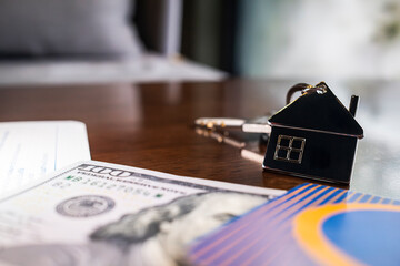 House key with home model and dollar banknotes on desk represents real estate investment, mortgage, property purchase, home loan, and financial planning for buying or selling residential property.