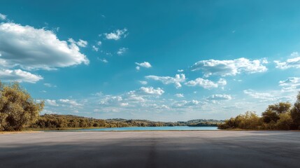 Fototapeta premium Serene Lake Under Clear Blue Sky with Fluffy White Clouds and Green Trees