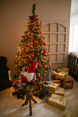 Designer Christmas tree decoration with lights. Concept for New Year and Christmas celebrations. Gifts in artisanal packaging under the tree.