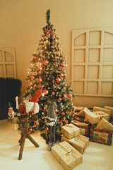 Designer Christmas tree decoration with lights. Concept for New Year and Christmas celebrations. Gifts in artisanal packaging under the tree.