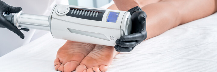 cosmetologist in rubber gloves doing endospheres therapy on female feet