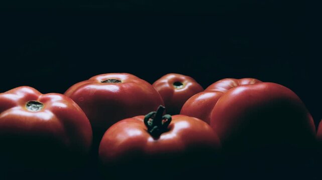 A close-up shot of several ripe, large, red Beefeater tomatoes on a dark background. They are slightly ribbed, some with visible stems or scars, and have meaty flesh.