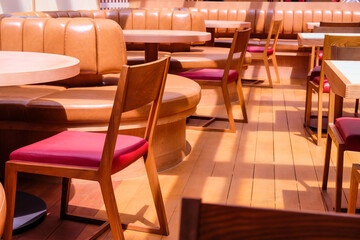 Wooden chairs and tables in a row in the interior of a restaurant