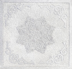 Detailed stone carving, with fluid organic shapes, set against a textured stone background