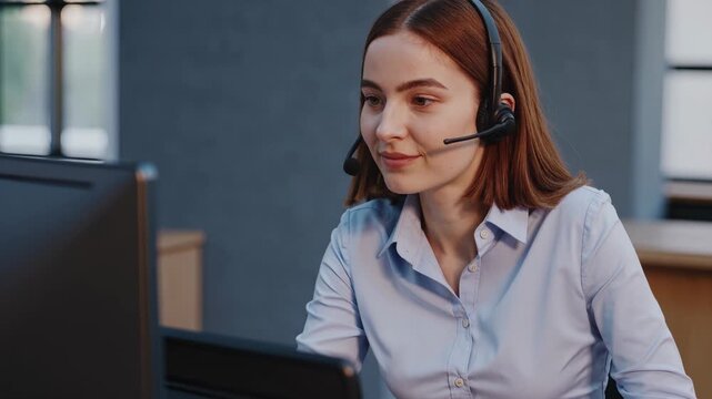 A female operator provides customer support in a call center. This woman works at a computer wearing a headset. The customer service operator offers friendly support. This woman is a professional supp