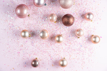 Christmas decoration of different elegant balls on pink background with glitter. Flat lay, top view
