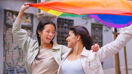 Diverse lesbian couple celebrating love holding pride flag