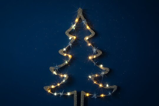 A sparkling christmas tree light outline glows against a deep blue background