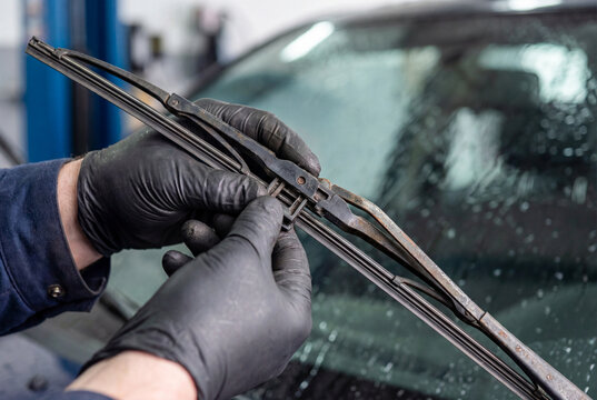 Mechanic hands changing car windshield wiper blade. Auto service replacement part