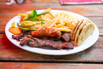 Appetizing combination plate of grilled meat with vegetables and tortillas.