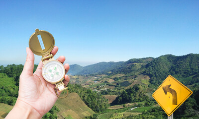 Compass in girl hand with road sign over mountain background, Navigation tool for tourism and direction of travel