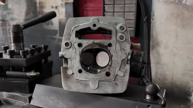 Close-up of a dirty internal combustion engine cylinder head undergoing maintenance in a workshop. Motorcycle Machine Part