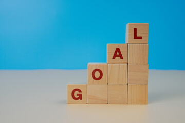 Wooden blocks arranged in ascending steps forming the word GOAL, symbolizing achievement, target setting, progress, motivation, business planning, and personal development.
