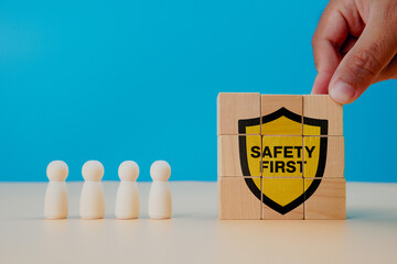 Safety awareness concept. Hand arranging wooden blocks showing a yellow shield with “Safety...