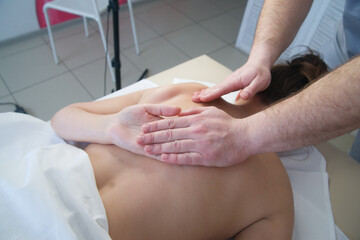 Fototapeta premium Close-up of skilled hands massaging a woman's back, promoting relaxation and relieving muscle tension.