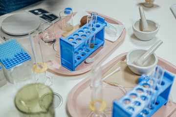 A well-organized lab table featuring test tube racks, beakers, mortars and pestles, and pipettes arranged on trays for an experimental procedure or demonstration