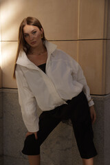 beautiful woman with dark hair in elegant clothes posing on the city street