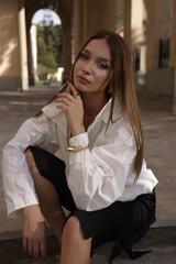 beautiful woman with dark hair in elegant clothes posing on the city street