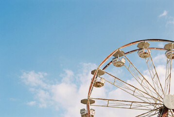 Minimalist view of a Ferris wheel part against a clear blue sky with ample negative space.