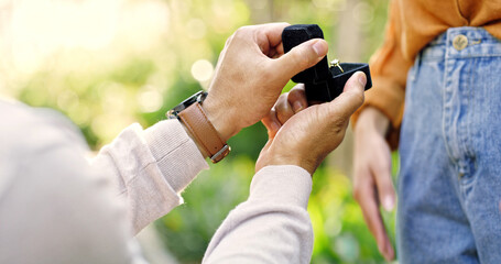 Hands, couple and proposal with ring outdoor for marry me gesture, engagement and save the date. Bokeh, people and partner with diamond jewellery, marriage promise and relationship commitment at park