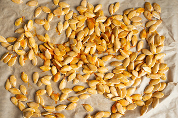 Pumpkin seeds scattered on parchment paper in natural light  