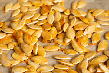 Closeup of roasted pumpkin seeds on parchment paper background  