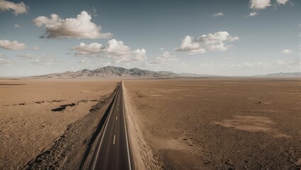 High-angle view of a straight road through a vast, arid landscape.  Vast desert stretches to a distant mountain range
