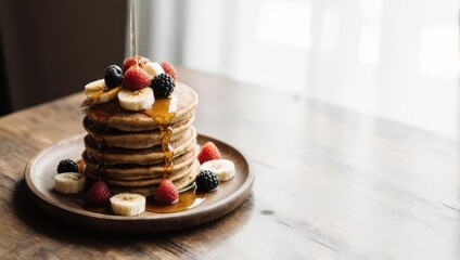 Stack of pancakes, topped with fresh berries, bananas, and drizzled with honey