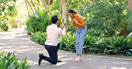 Couple, surprise and proposal with ring at park for marry me gesture, engagement and save the date. Unexpected, people or partner with marriage promise, emotional reaction and relationship commitment