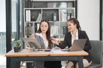 Asian businesswoman sitting at work using laptop talking and consulting in office