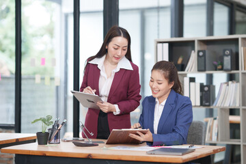 Asian businesswoman sitting at work using laptop talking and consulting in office