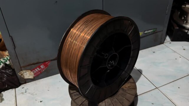 A large spool of copper-colored welding wire for industrial fabrication and repair tasks