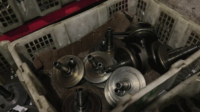 A collection of used motorcycle engine crankshafts and dismantled components are stored in a plastic crate. Motorcycle Machine Part