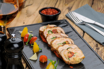 chicken meatloaf with ham and cherry tomatoes on a black rectangular plate macro photo