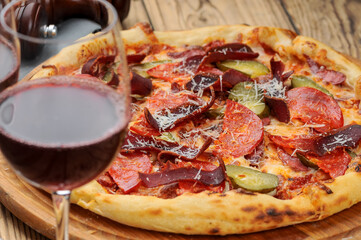 pizza with meat and bastrum close-up on the table with a glass of red wine