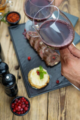 meatloaf sliced ​​on a black slate with a glass of wine in hands