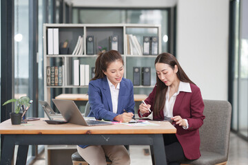 Asian businesswoman sitting at work using laptop talking and consulting in office