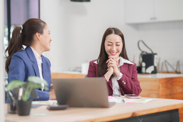 Asian businesswoman sitting at work using laptop talking and consulting in office