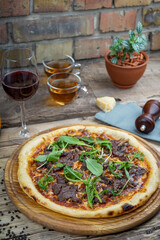 pizza with veal and fresh arugula on a wooden board