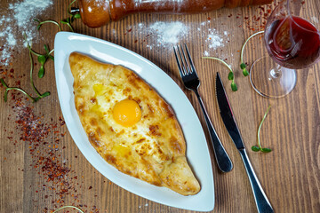 Khachapuri with cheese and egg yolk in a white plate
