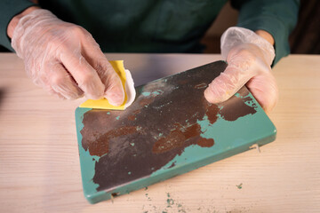 Man upcycling master working at home workshop, holding metallic part of lamp base and precisely...