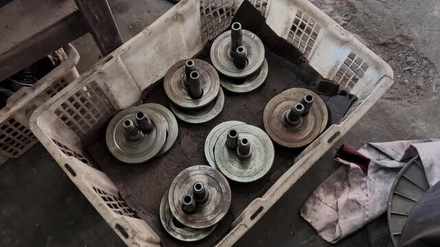 Close-up view of used crankshaft components stored in a dirty plastic crate
