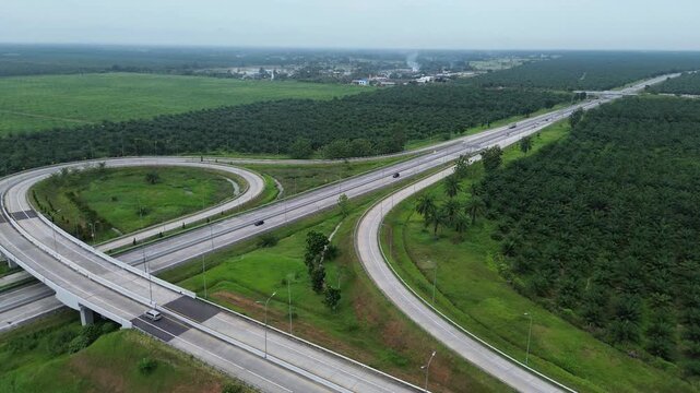Aerial view of toll roads in Indonesia from drone footage, toll roads surrounded by oil palm plantations